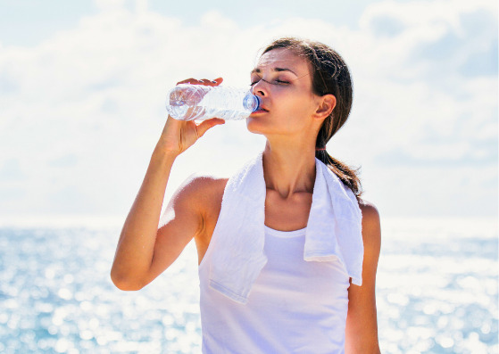 デトックスのため運動中にミネラルウォーターを飲む女性